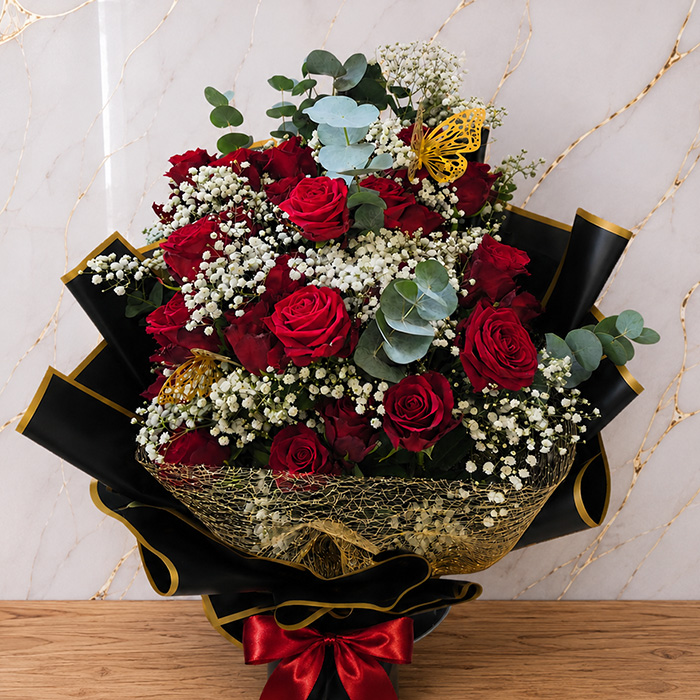 Eleganter roter Rosenstrauß mit Schleierkraut in schwarzer Verpackung